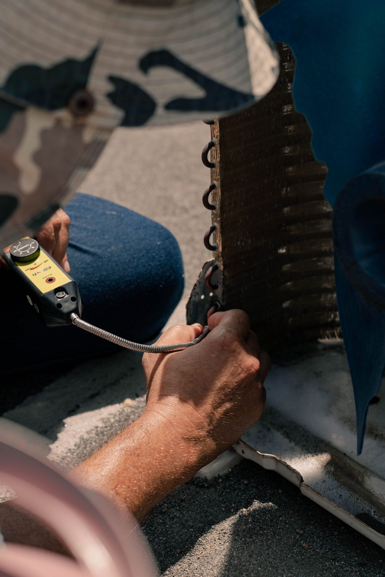 Close-up of a technician's hands repairing an air conditioner coil